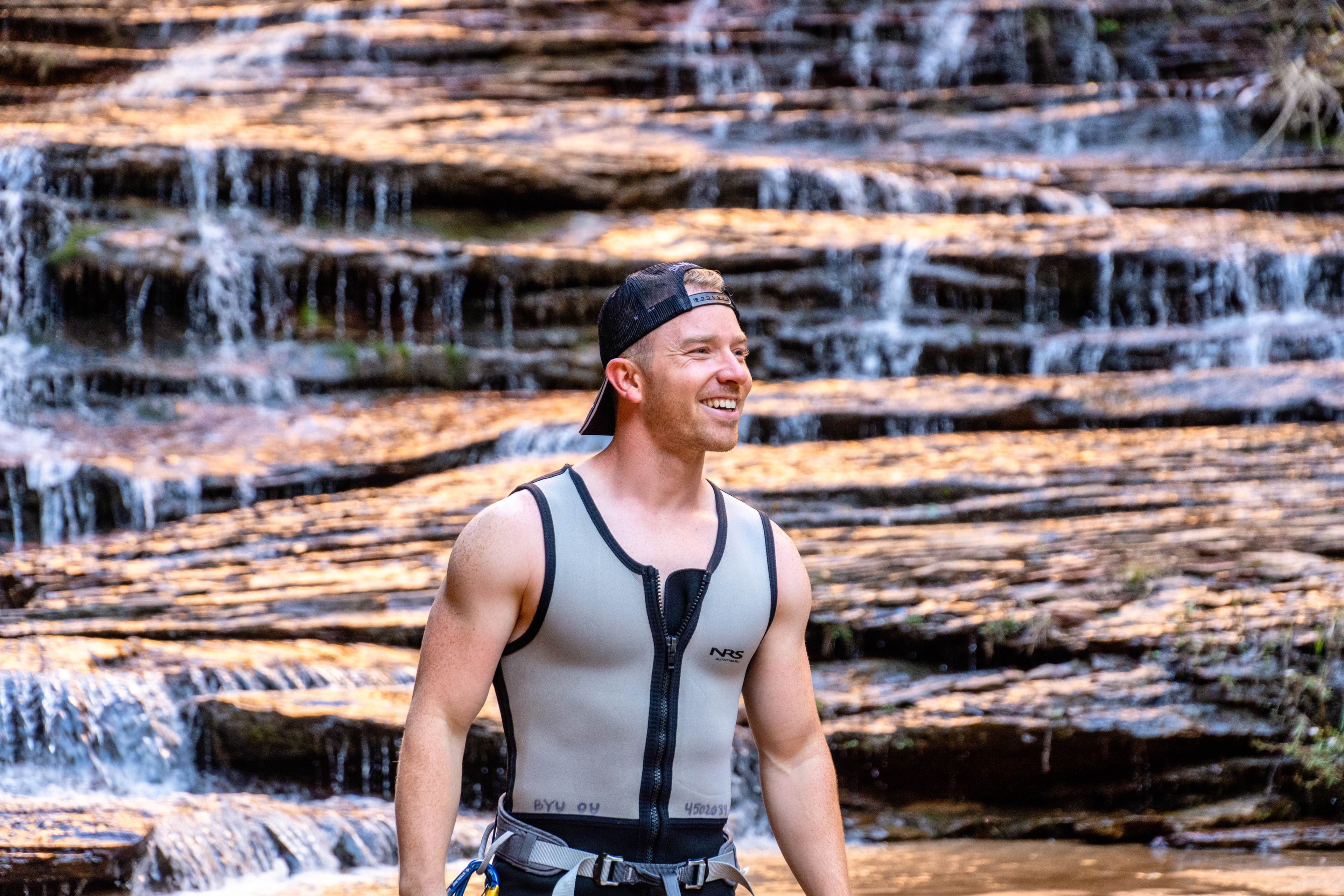 Peter smiling in front of a waterfall while canyoneering