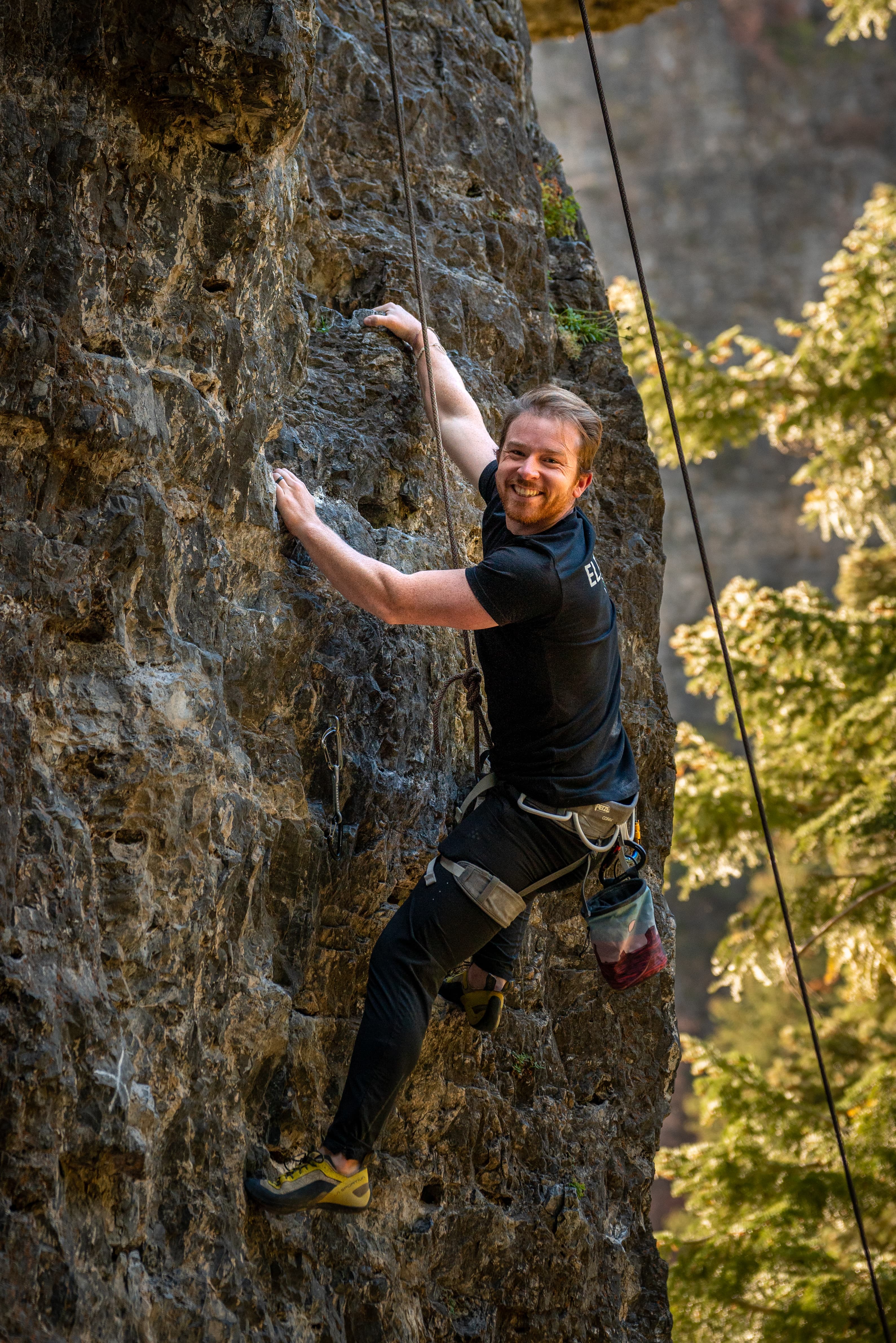 Peter rock climbing and smiling at the camera